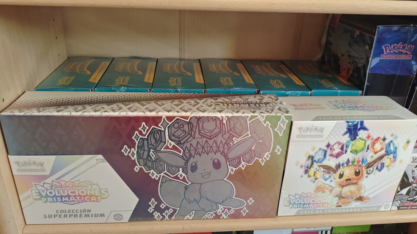 Colección Superpremium y Elite Trainer Boxes de Evoluciones Prismáticas sellados apilados en la estantería